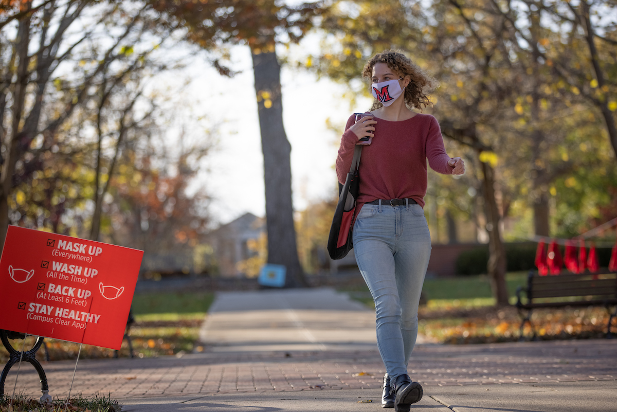 Miami student wearing a mask and walking across campus in the Fall