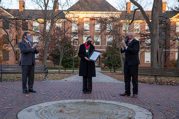 jason osborne, martha castaneda and gregory crawford stand at the university seal
