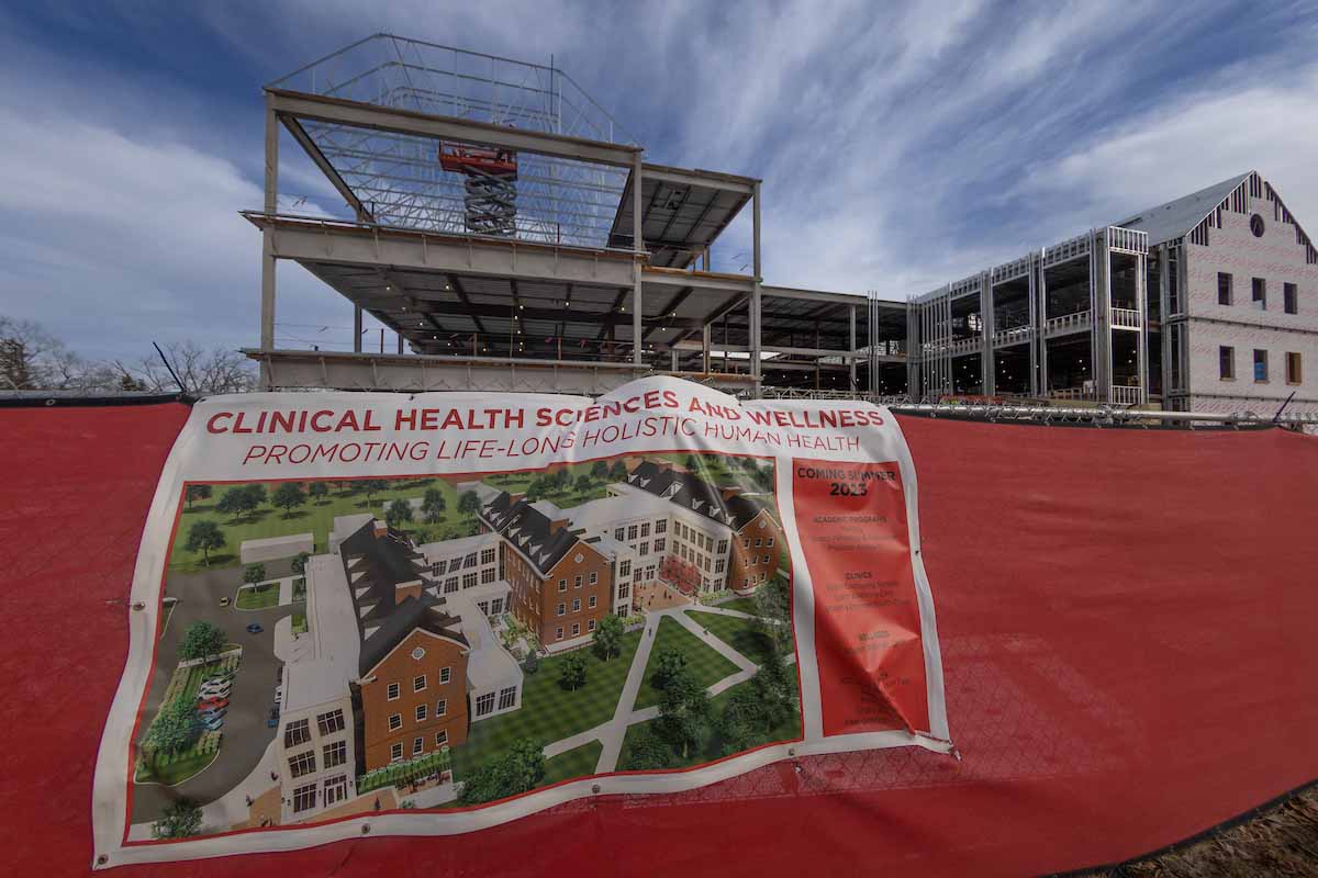 construction of the clinical health sciences and wellness building with a red fence and building sign in front