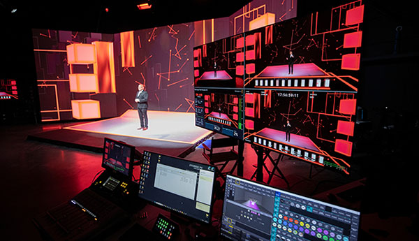 Miami University President Gregory Crawford welcomes the community to the dedication of McVey Data Science, from the building's Extended Reality (XR) Stage, with computer monitors in the foreground and images of constellations projected on the screen behind Crawford