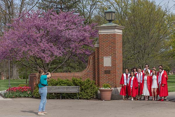 students in caps and gowns pose for a picture at the slant walk gates