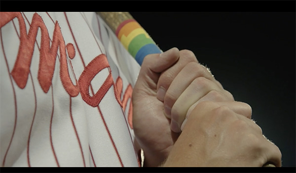 Close of Brian Zapp's hands holding a baseball bar with rainbow colored tape