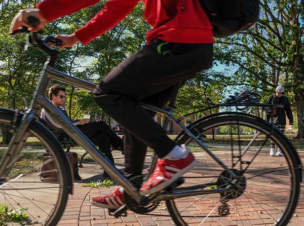 A student rides a bike near Bishop Woods