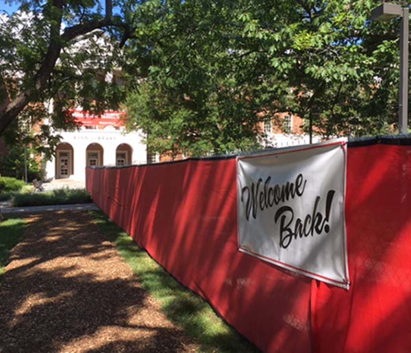 welcome sign on red fence near King Library