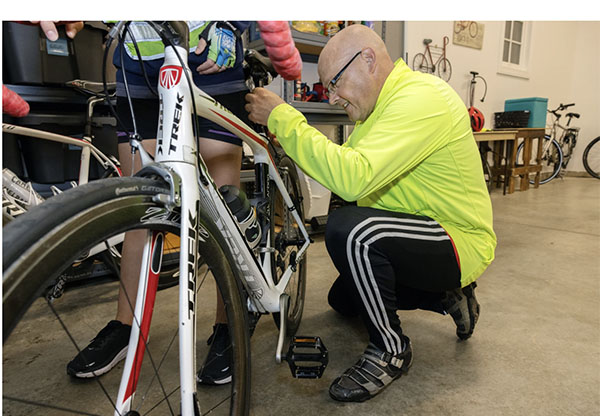 Greg Crawford adjusts pedals on a bicycle in his garage