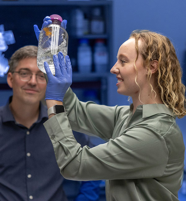 Cece Meinking holds a flask, and Kevin Yehl looks on 