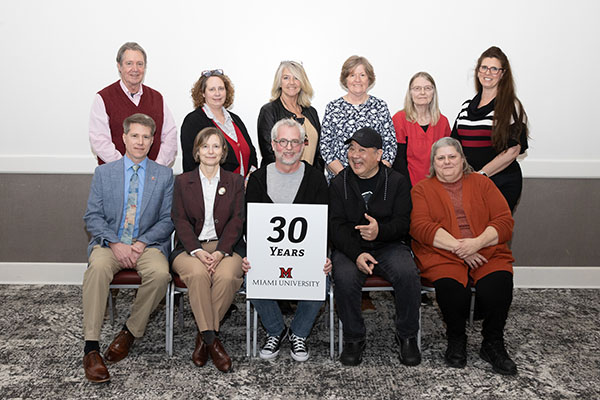 A  group of 11 Miami employees pose with a 30 years of service sign in the Dolibois room