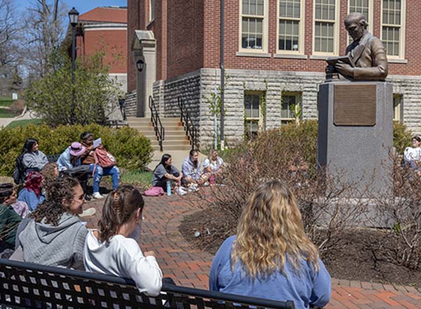 Students sit on the plaza behind McGuffey Hall near the McGuffey statue on a sunny spring day