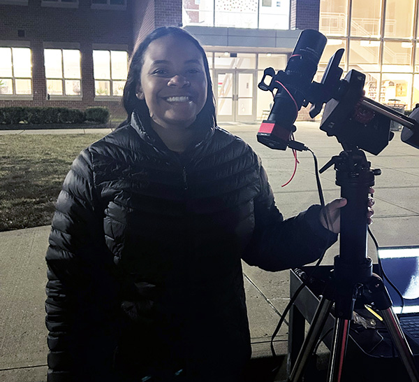 Olivia Freeman next to a telescope