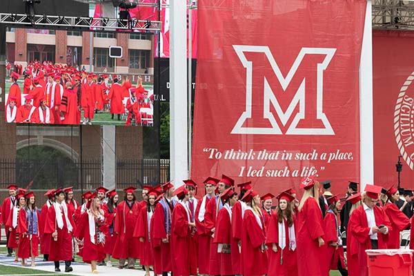 Graduating students in their caps and gowns gather in the plaza outside Yager stadium before commencement  