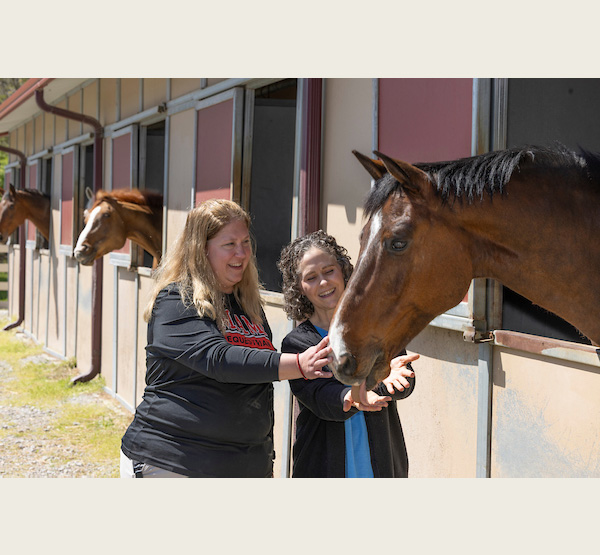 Heather Pinnick, director of the equestrian center, (left) and Jennifer Young, a licensed psychologist and associate director for community engagement in the Student Counseling Service, pet Hendrix.