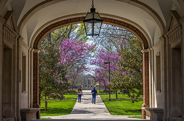 Upham arch in spring with 2 students walking on a path toward the arch