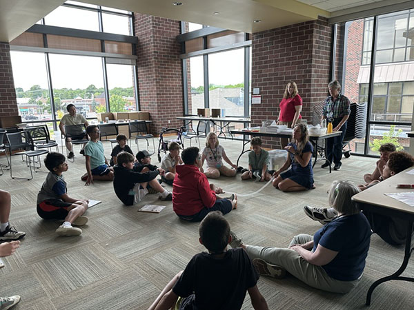 middle school students sit on the floor at Lane Library and watch a physics demonstration