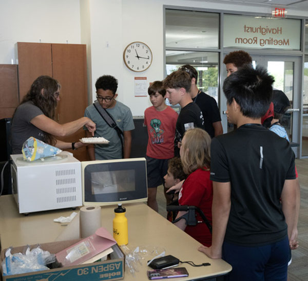 Heidi Schran shows middle school students a plate of microwaved marshmallows
