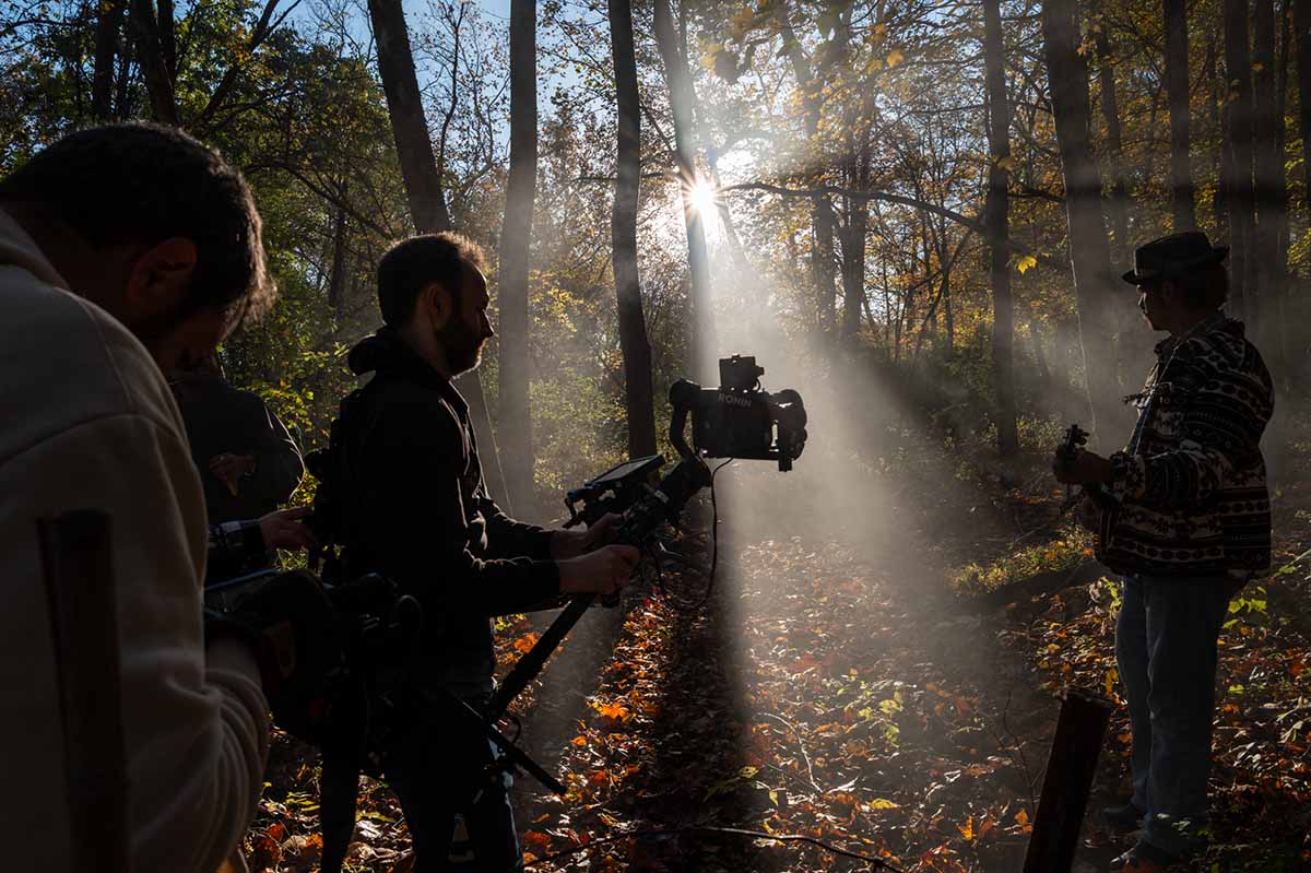 John Hicks '26 plays the banjo Marc van Osdale, director of photography and colorist, in the middle with camera, films Glee Club member and banjo player John Hicks '26. Director Ryan Parma is at left